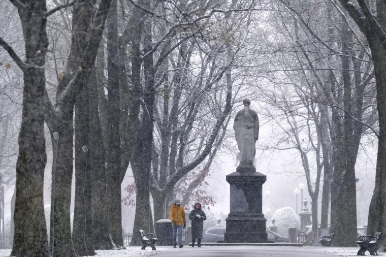 Zdjęcie: pada śnieg, gdy para spaceruje wzdłuż centrum handlowego Commonwealth Avenue w dzielnicy Back Bay w Bostonie, 20 grudnia 2024 r.