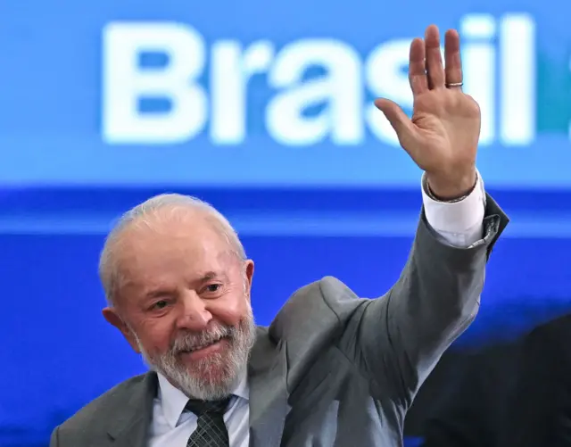 Lula kiwa głową ręką i uśmiecha się